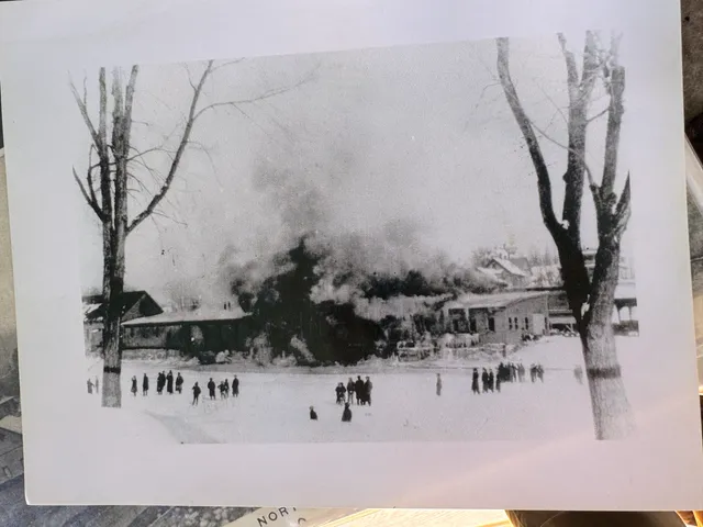 A building fire in the village, watched by a crowd of villagers standing on the frozen pond.